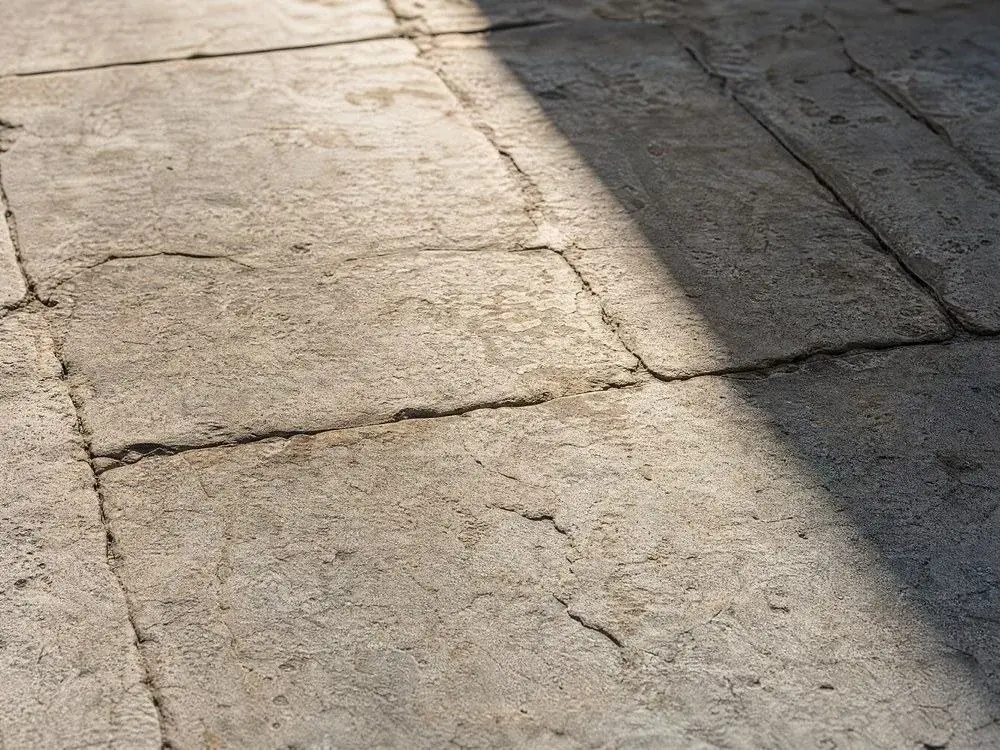 Abgetretene helle Steinplatten mit einem harten diagonalen Schatten