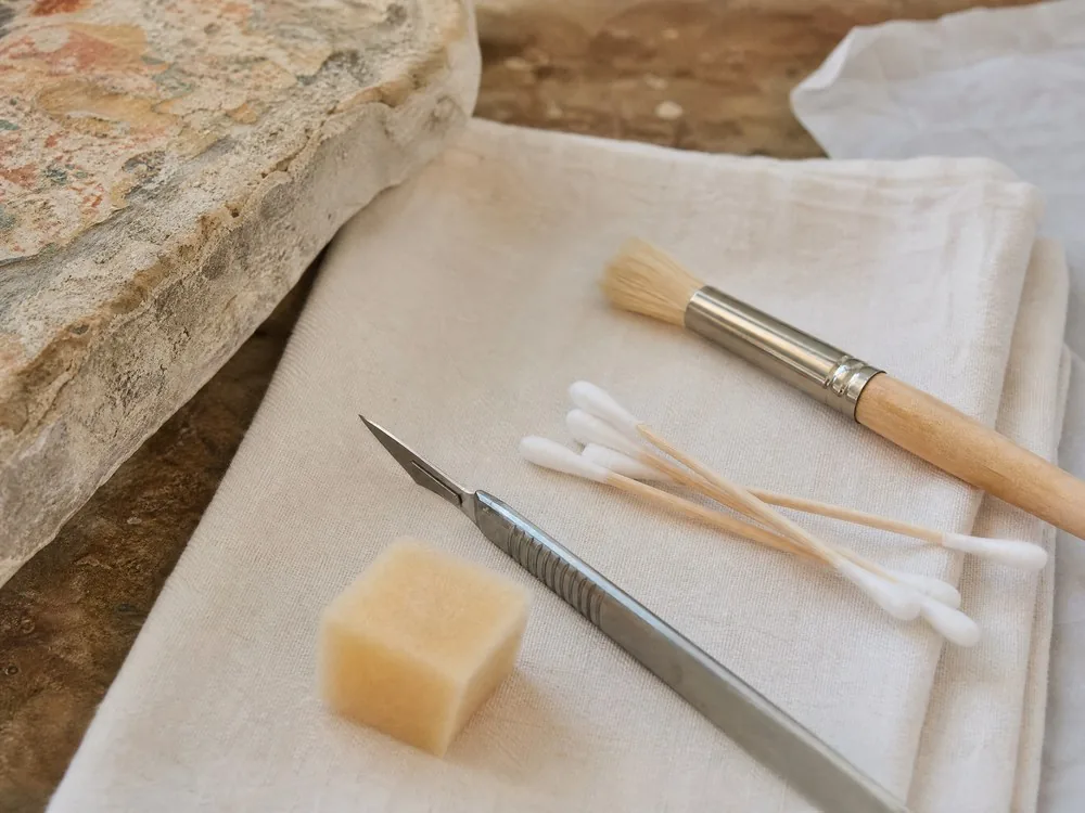 Skalpell, Tupfer und weicher Pinsel eines Restaurators auf einem gefalteten Tuch